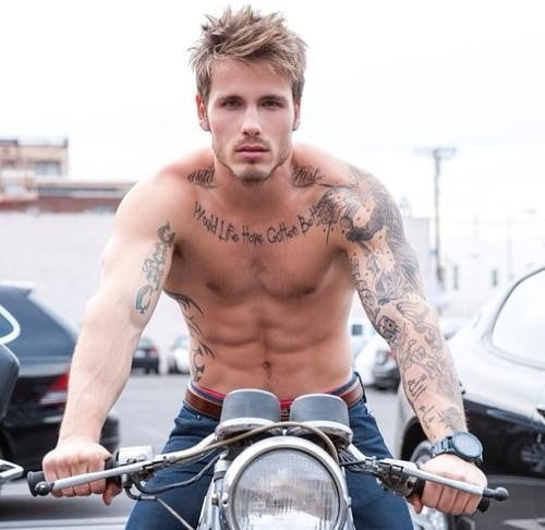Sexy getatoeëerde man op motorfiets